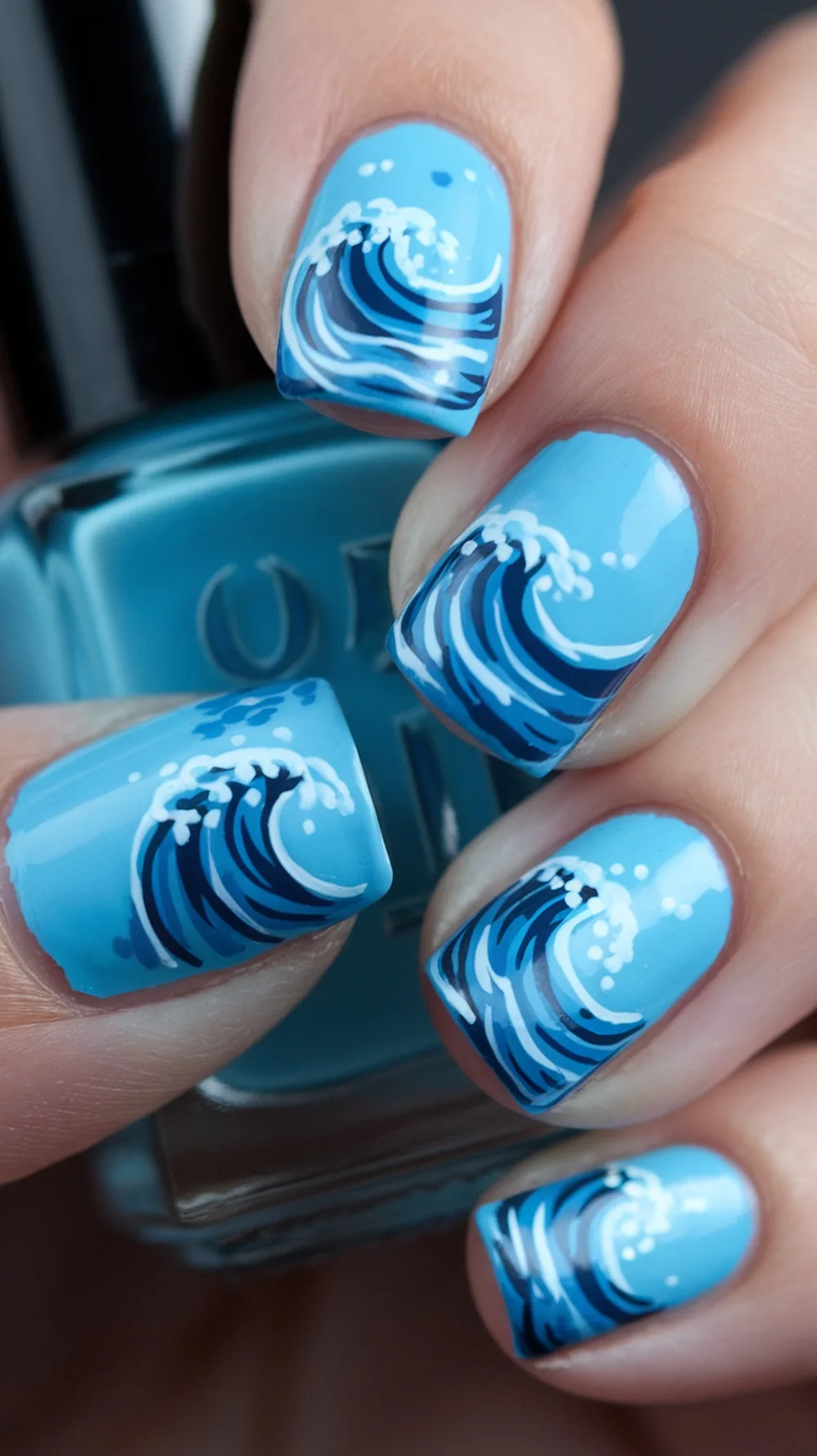 Nail art featuring ocean wave designs with shades of blue and white accents.