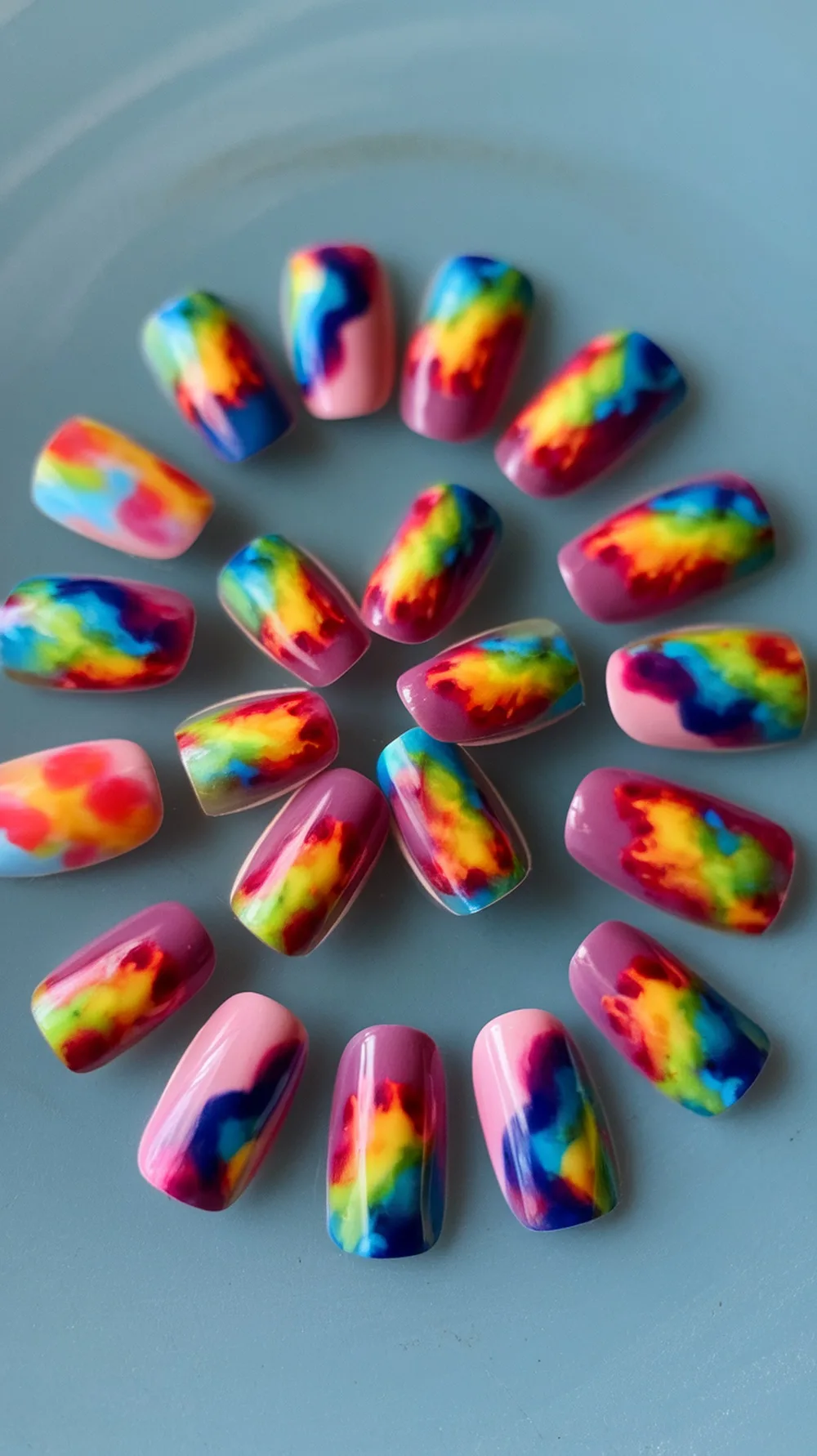 Colorful tie-dye nail art with various designs on false nails