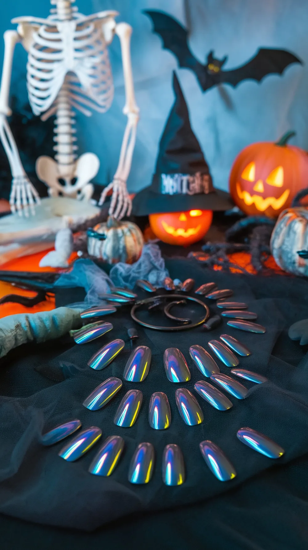 A collection of holographic nail designs displayed among Halloween decorations like pumpkins and a skeleton.