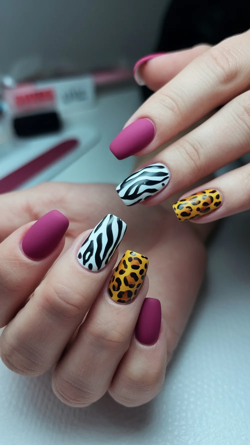 Nails featuring animal print accents with zebra and leopard designs, alongside a solid mauve color.