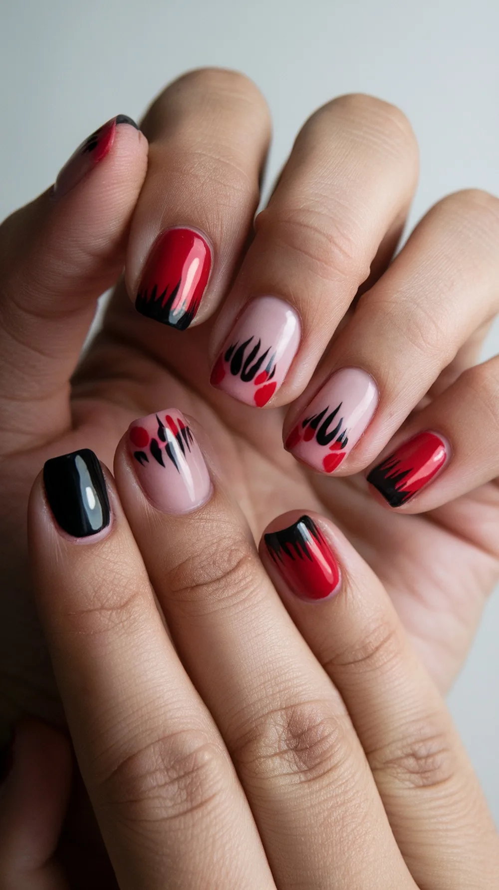 Nail design featuring red and black colors resembling vampire bites.
